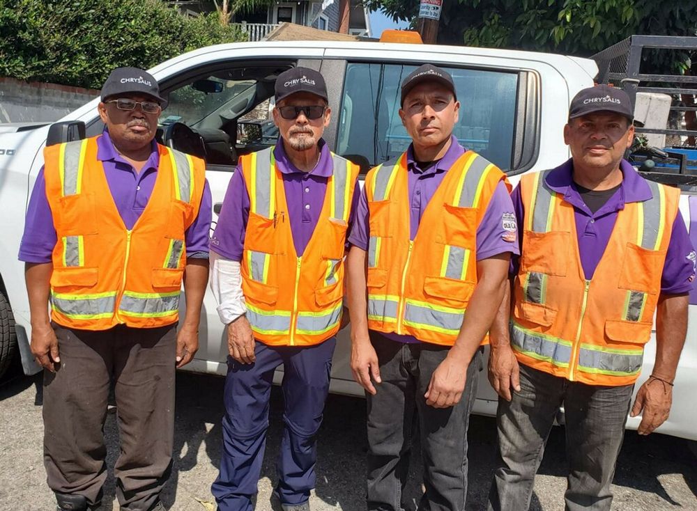 The North Figueroa Clean Team in purple shirts and safety vests beside their truck
